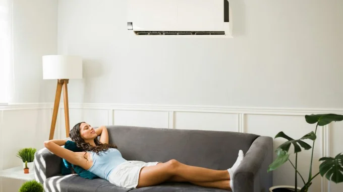 Девушка лежит под кондиционером, который включила кнопкой
