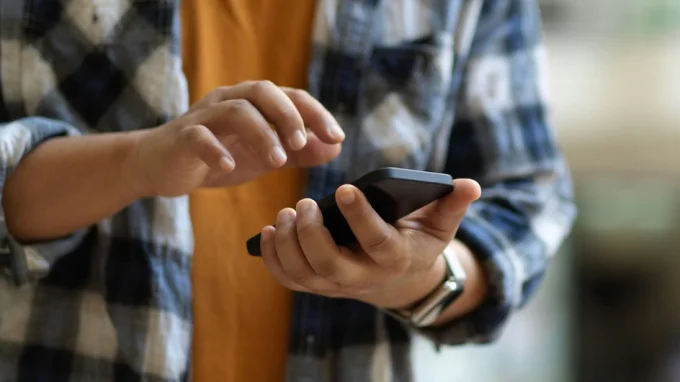 Мужчина вводит команду в айфоне, чтобы отправить СМС