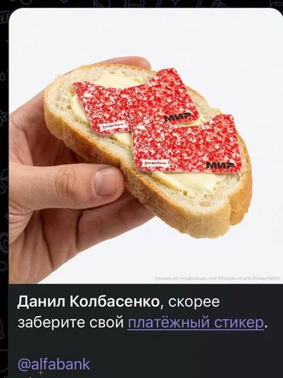 Рука держит ломоть хлеба с маслом, на котором лежат два красных платежных стикера с логотипом «Мир». Внизу рекламный текст с обращением к конкретному человеку и ссылкой банка.